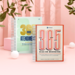 Cadernos "365 dias" em fundo rosa e plantas.